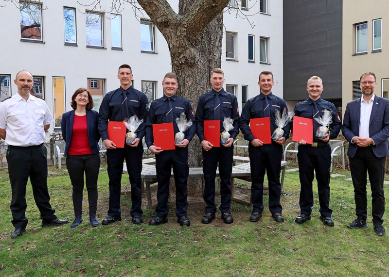 OB Thomas Nitzsche (r.), Nick Ludwig, stellvertretender Fachdienstleiter Feuerwehr (l.), und Antonia Erdmann, Ausbildungskoordinatorin, gratulieren den neuen Feuerwehr-Anwärtern.